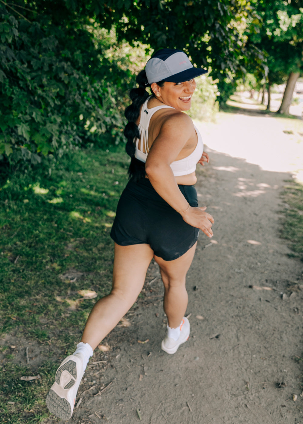Oiselle Five Panel Running Hat, woman running on a dirt path