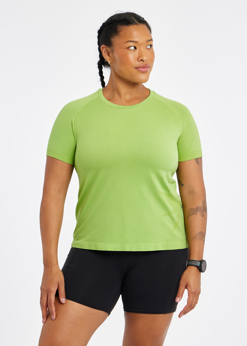 Woman wearing a green running short sleeve and black compression shorts, front view