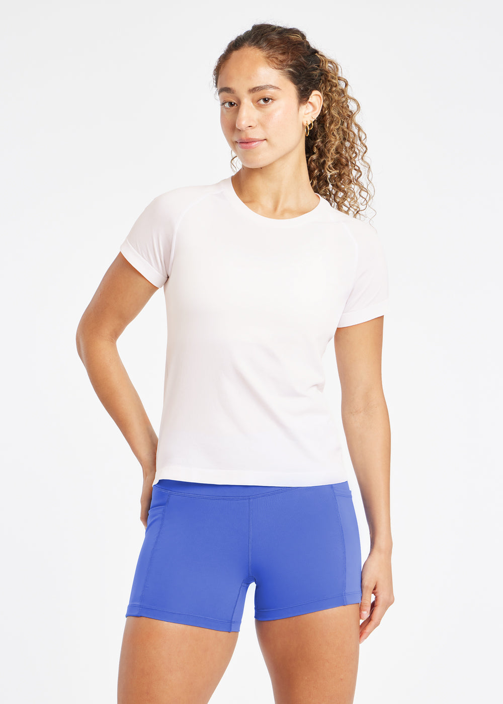 Woman wearing a white running short sleeve and blue compression shorts, front view