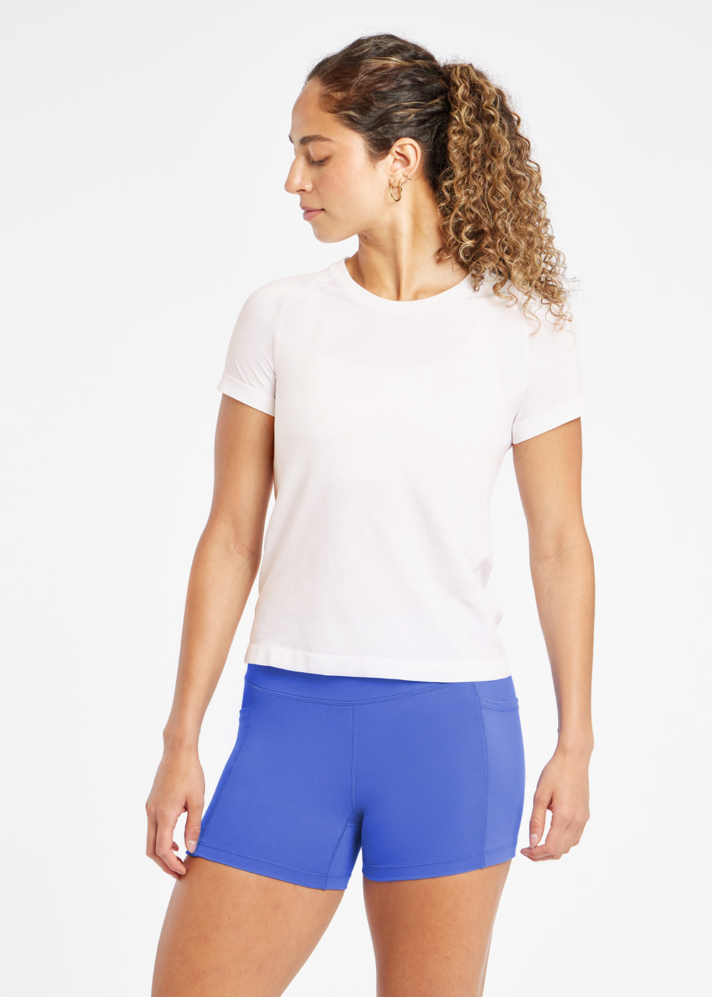 Woman wearing a white running short sleeve and blue compression shorts, back view