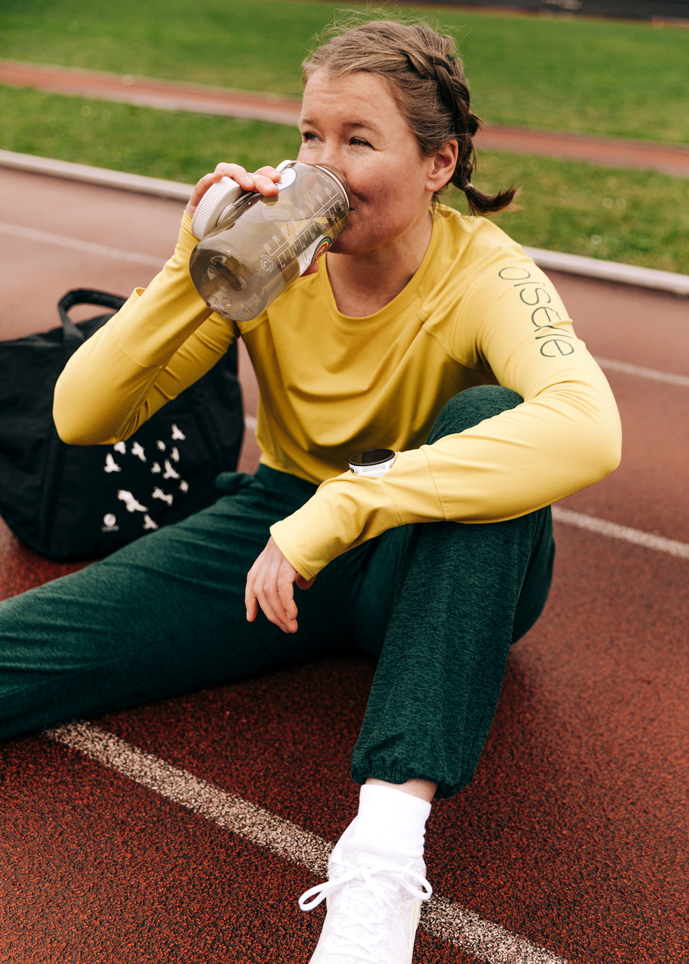 Lux Sweatpants in Juniper Green, woman on track drinking water